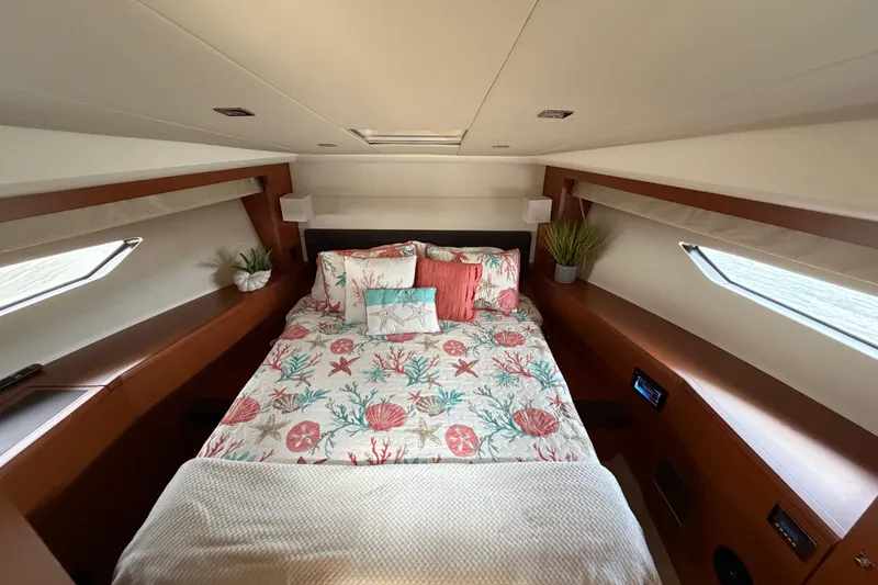 Slide: The Image of Luxurious 2012 Prestige 500S yacht bedroom with nautical-themed bedding and elegant wood accents. - 28