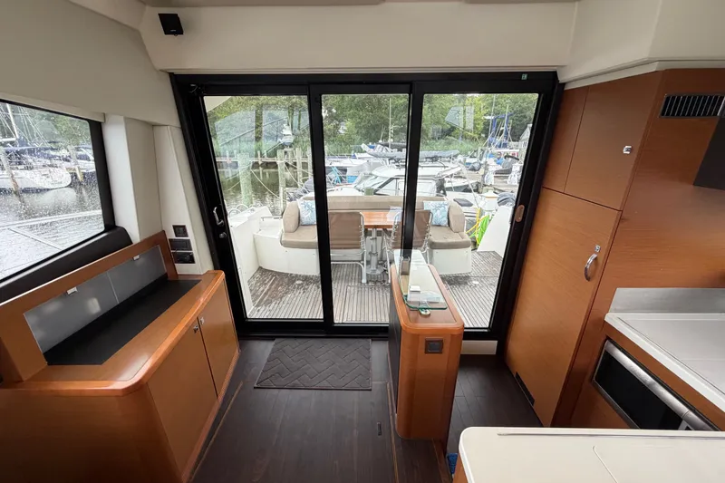 Slide: The Image of Interior view of a 2012 Prestige 500S yacht, featuring sleek wood finishes and marina backdrop. - 80
