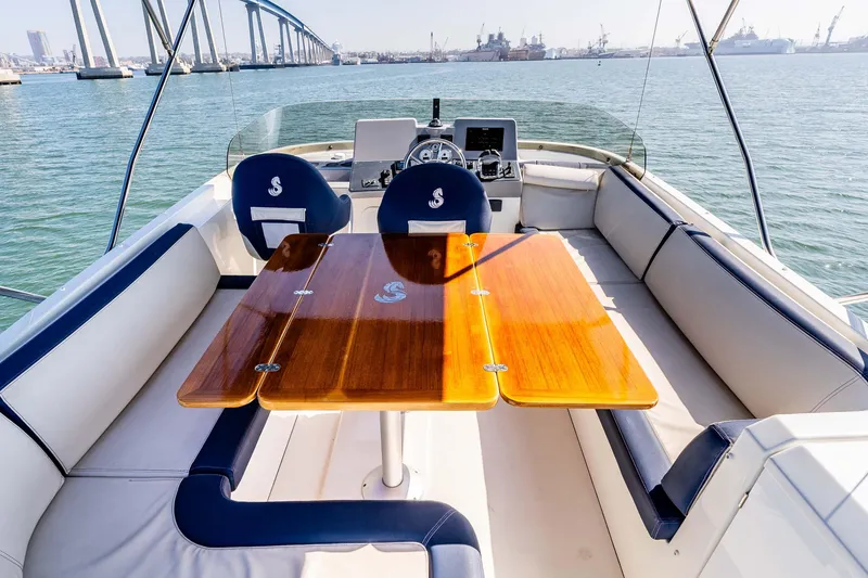 Slide: The Image of 2019 Beneteau Swift Trawler 44 interior with wooden table and seating, overlooking a scenic harbor. - 14