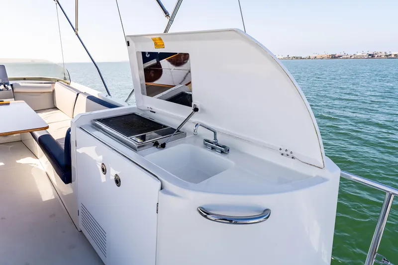 Slide: The Image of Outdoor kitchenette on 2019 Beneteau Swift Trawler 44, featuring a sink and grill, overlooking water. - 15