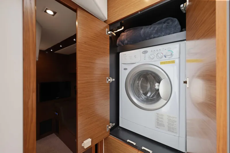 Slide: The Image of Laundry area with washer in 2016 Cruisers Yachts 45 Cantius, featuring wooden cabinetry. - 49
