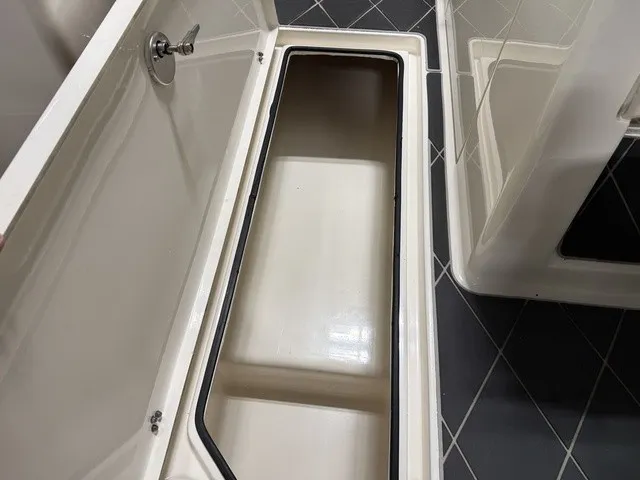 Slide: The Image of An open storage compartment on a 2020 Cobia 240DC boat, featuring a clean, white interior. - 24
