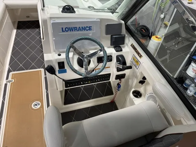 Slide: The Image of The cockpit of a 2020 Cobia 240DC with a Lowrance navigation system and cushioned steering wheel. - 20