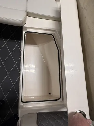 Slide: The Image of An open storage compartment on a 2020 Cobia 240DC boat with cushioned seating. - 31