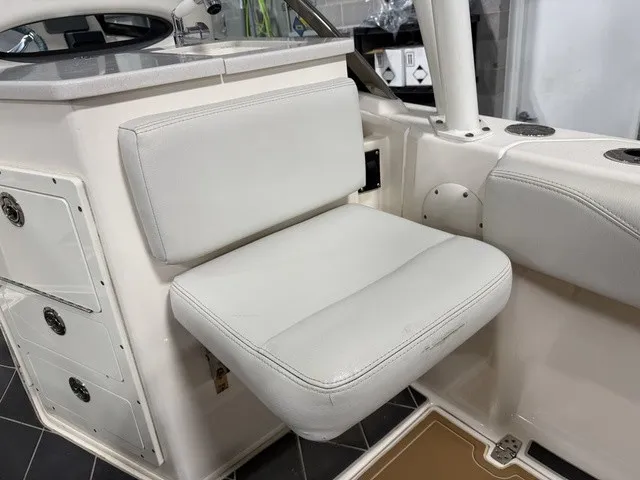 Slide: The Image of A white seat on a Cobia 240DC boat, surrounded by storage compartments and fixtures. - 14