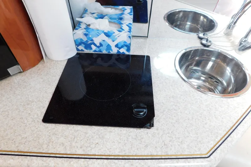 Slide: The Image of 2006 Fountain 38 LX yacht kitchen with stovetop, sink, and tissue box on countertop. - 51