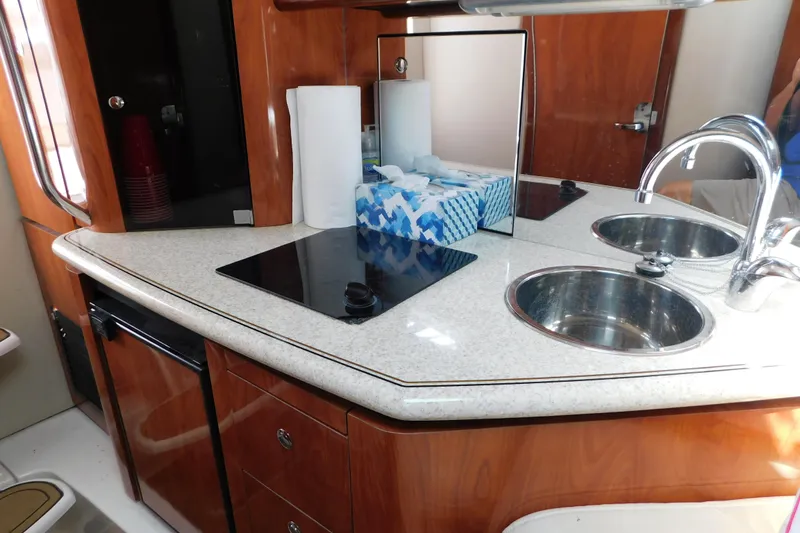 Slide: The Image of 2006 Fountain 38 LX yacht kitchen with dual sinks, stovetop, and wooden cabinetry. - 49