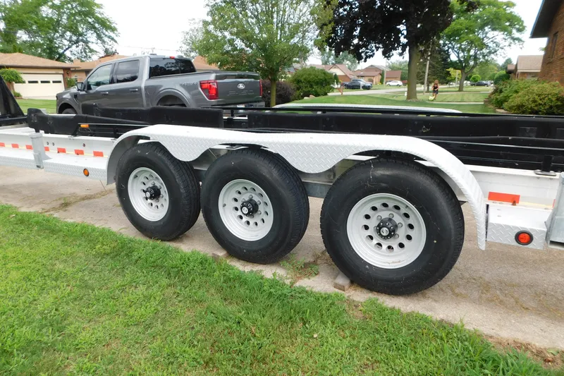 Slide: The Image of Triple-axle trailer parked on driveway, with a gray truck in the background. - 84