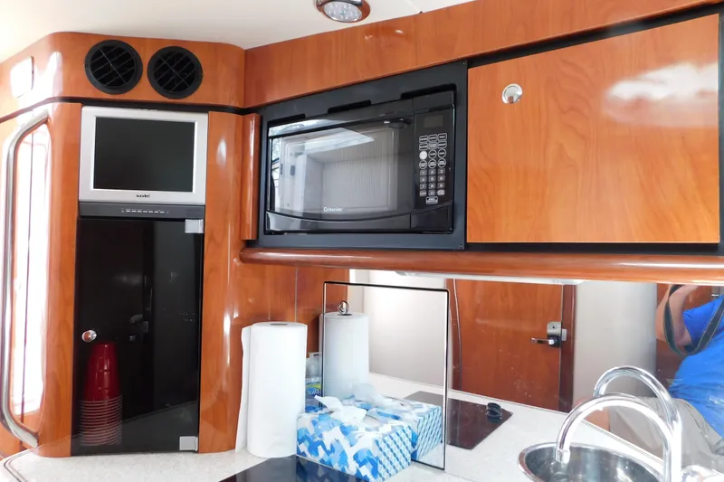 Slide: The Image of 2006 Fountain 38 LX yacht interior with microwave, TV, and wooden cabinetry. - 50