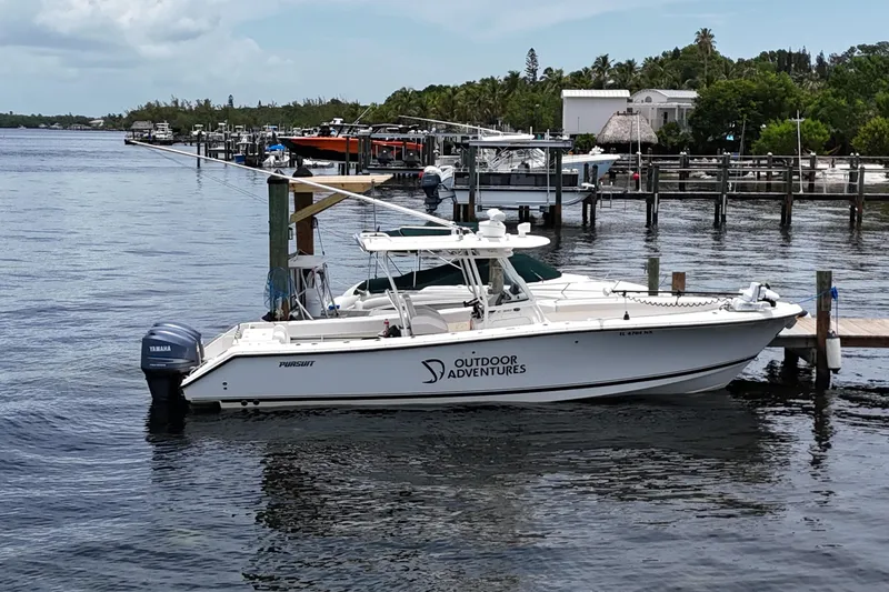 The Image of 2009 Pursuit C 310 Center Console boat docked at marina, labeled "Outdoor Adventures." - 0