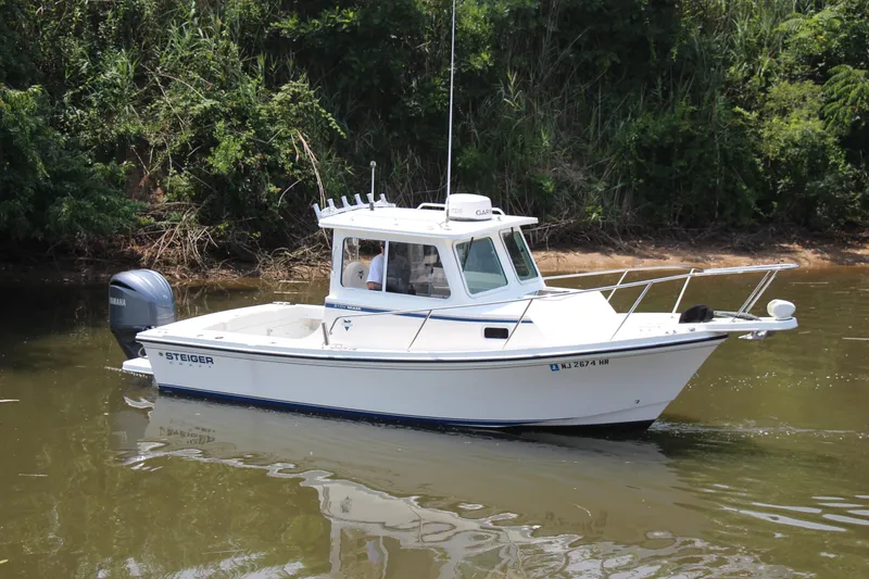 Slide: The Image of 2022 Steiger Craft 21 Miami boat cruising on a calm river near lush greenery. - 15