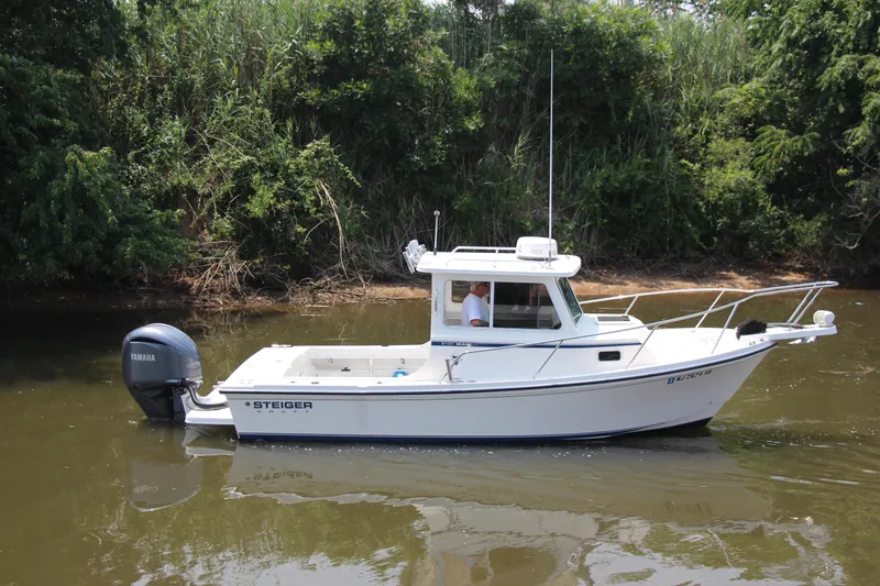Slide: The Image of 2022 Steiger Craft 21 Miami boat on calm water, surrounded by lush greenery. - 14