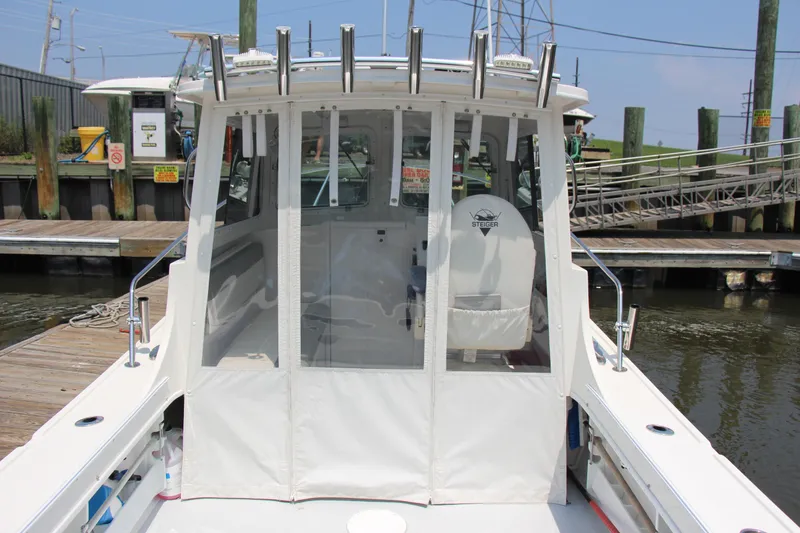 Slide: The Image of 2022 Steiger Craft 21 Miami boat docked, featuring enclosed cabin and fishing rod holders. - 22