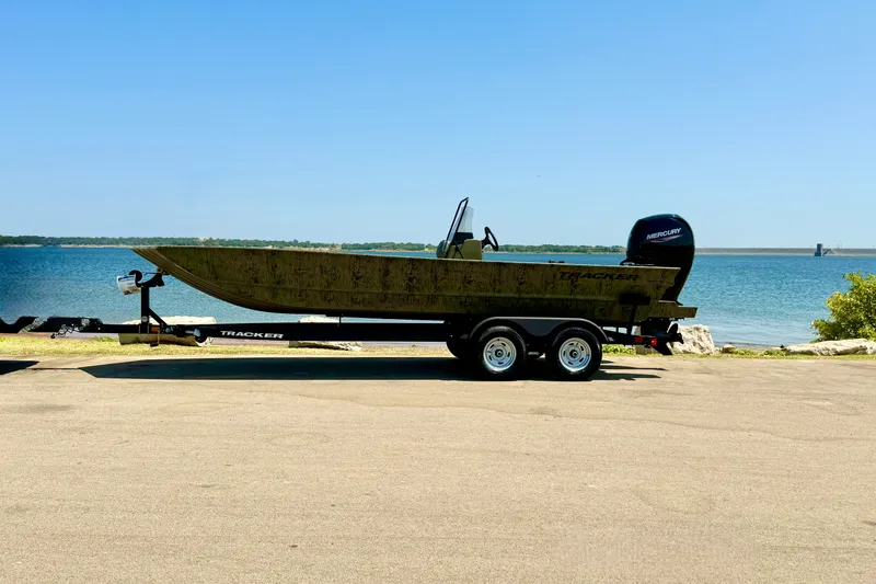 Slide: The Image of 2026 Tracker Grizzly 2072 CC boat on trailer by a lake. - 15