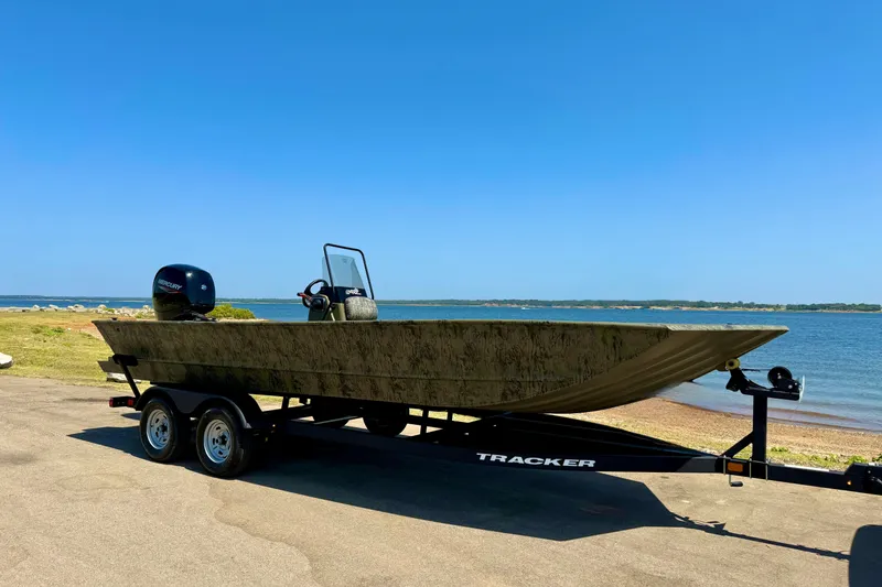 The Image of 2026 Tracker Grizzly 2072 CC boat on trailer by a scenic lakeside. - 0