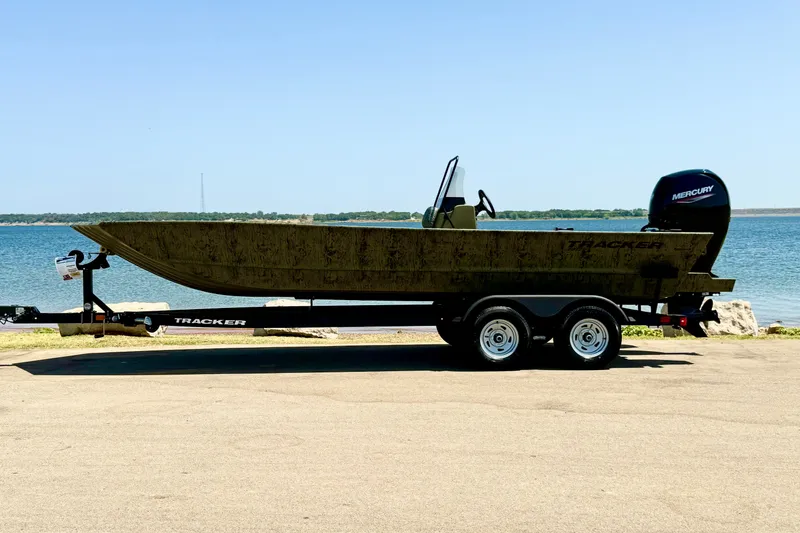 Slide: The Image of 2026 Tracker Grizzly 2072 CC boat on trailer by a lake. - 14