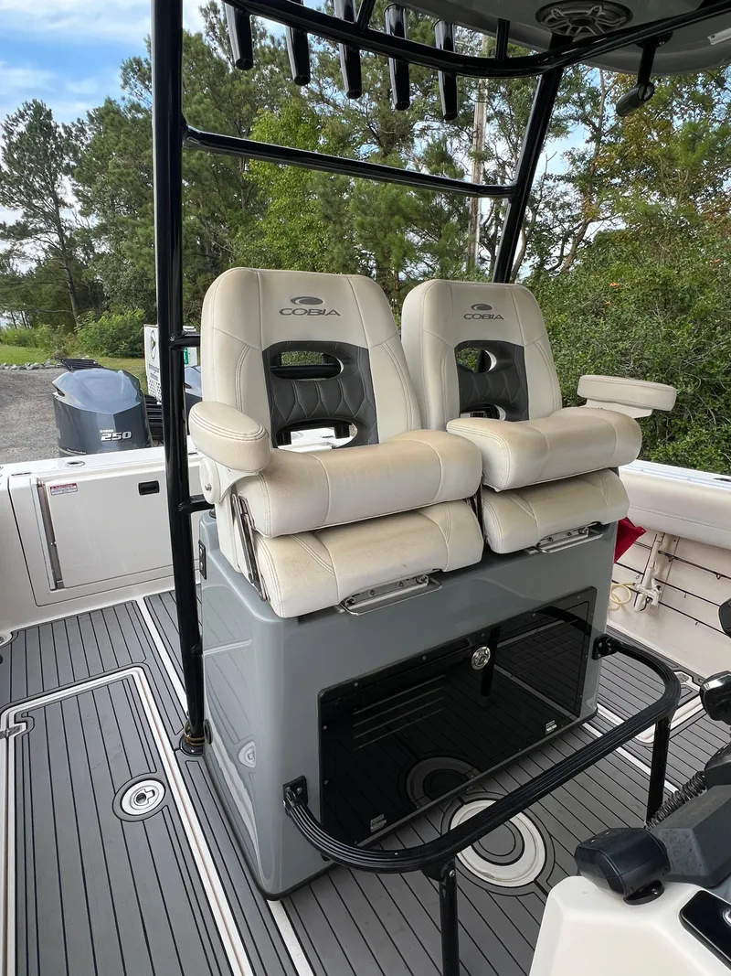 Slide: The Image of Two cushioned captain's chairs on a Cobia 280 Center Console boat, surrounded by trees. - 6