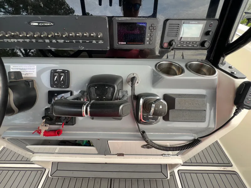 Slide: The Image of The image shows the helm of a 2020 Cobia 280 Center Console boat. It features modern navigation and communication equipment, along with cup holders. - 10