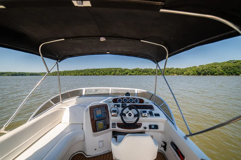 Slide: The Image of 2005 Meridian 341 Sedan boat helm with lake view and lush green shoreline. - 56