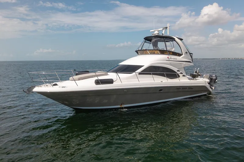 Slide: The Image of 2006 Sea Ray 455 Sedan Bridge yacht on calm ocean waters under a partly cloudy sky. - 4