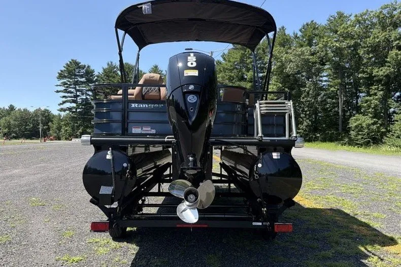 Slide: The Image of 2026 Ranger 220FC pontoon boat with outboard motor, parked on gravel, surrounded by trees. - 10