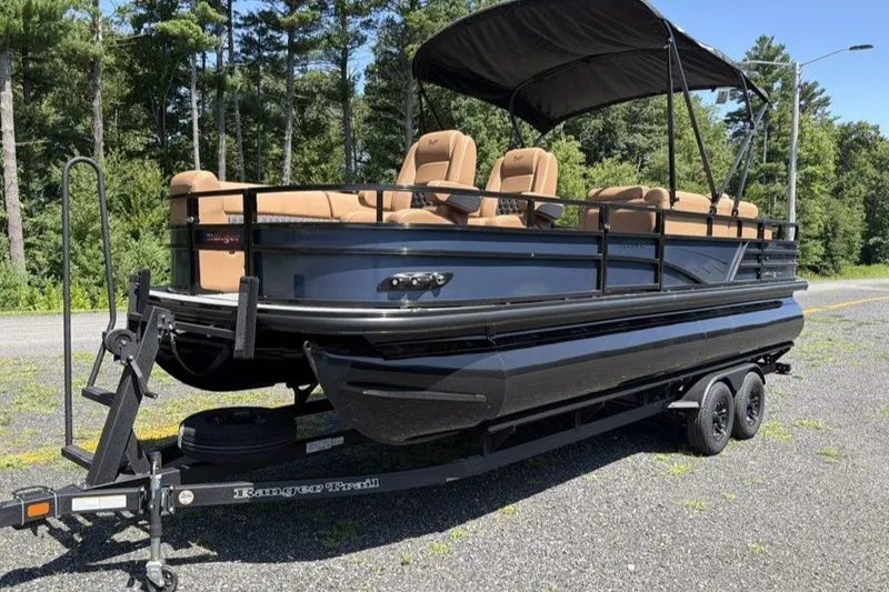 The Image of 2026 Ranger 220FC pontoon boat on trailer, featuring tan seating and black canopy. - 0