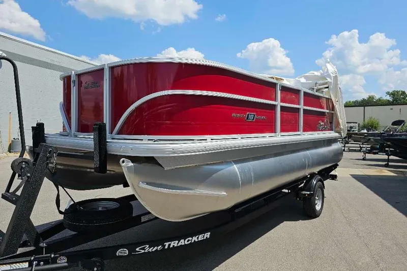 The Image of 2026 Sun Tracker Party Barge 18 DLX pontoon boat on trailer, red and silver design. - 0