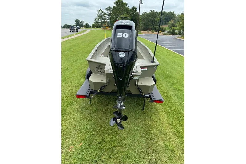 Slide: The Image of 2026 Tracker Grizzly 1650 T Prairie Wings Edition boat with Mercury outboard motor on grass. - 2