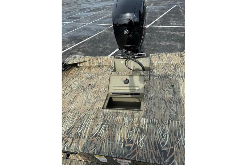 Slide: The Image of 2026 Tracker Grizzly 2072 CC boat with camouflage design and outboard motor in parking lot. - 13