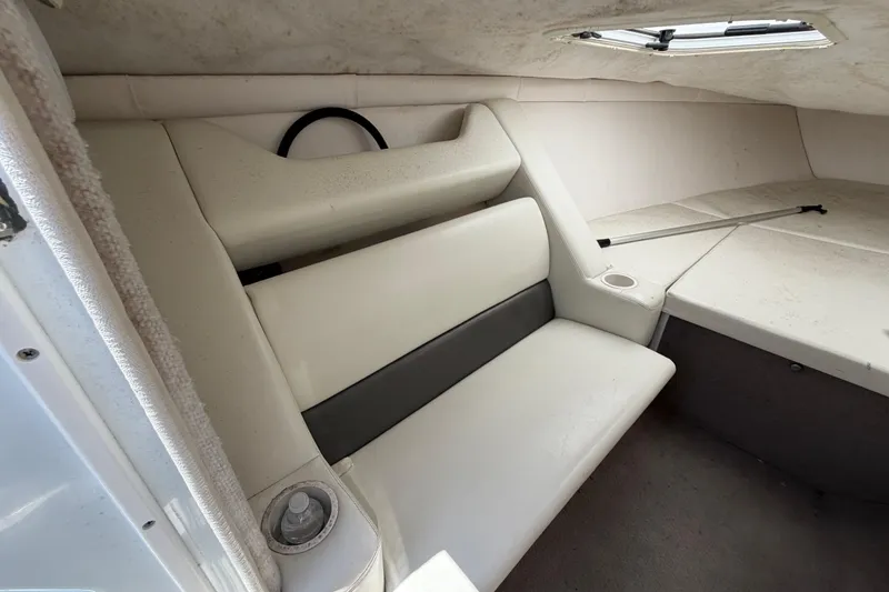 Slide: The Image of Interior of a 2002 Baja 25 Outlaw boat, featuring white seating and a small window. - 23