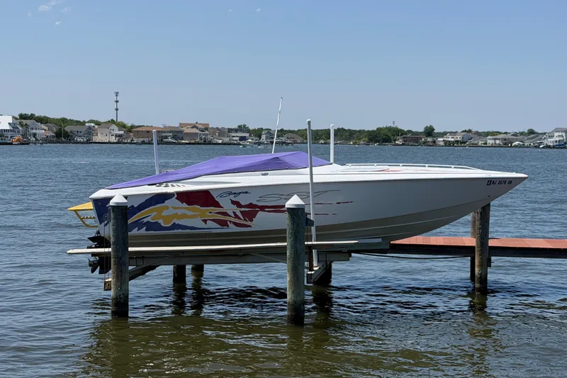 Slide: The Image of 2002 Baja 25 Outlaw speedboat docked on a lift, featuring vibrant graphics and a purple cover. - 5