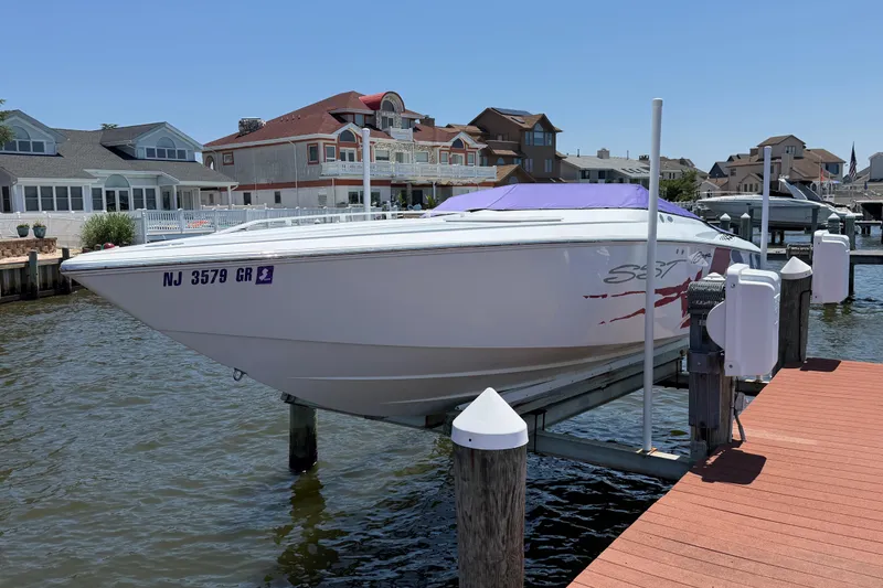 Slide: The Image of 2002 Baja 25 Outlaw speedboat docked at a marina, surrounded by waterfront homes. - 10