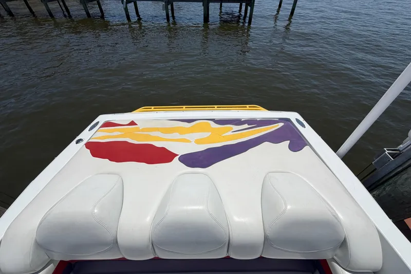 Slide: The Image of 2002 Baja 25 Outlaw boat with colorful deck design, docked by the water. - 12