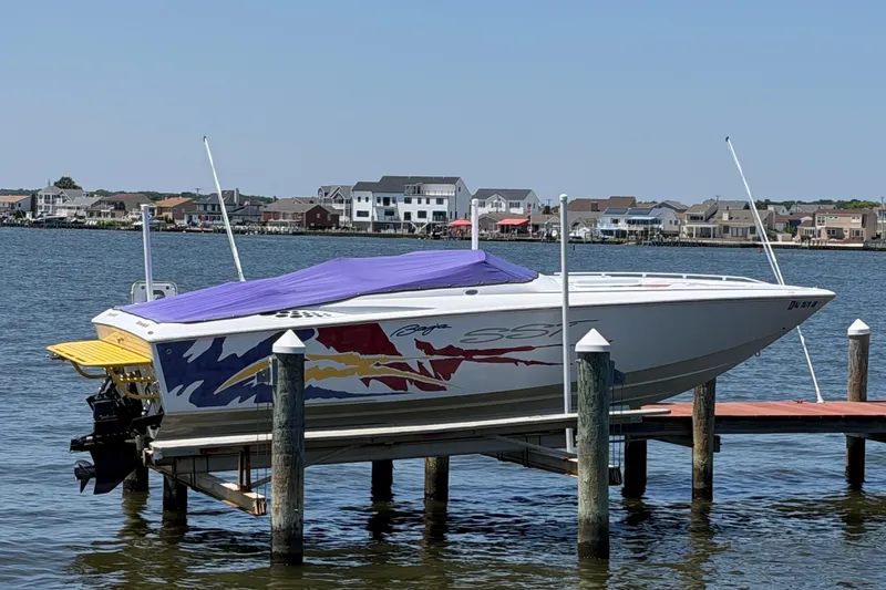Slide: The Image of 2002 Baja 25 Outlaw speedboat with vibrant graphics docked by waterfront homes. - 6