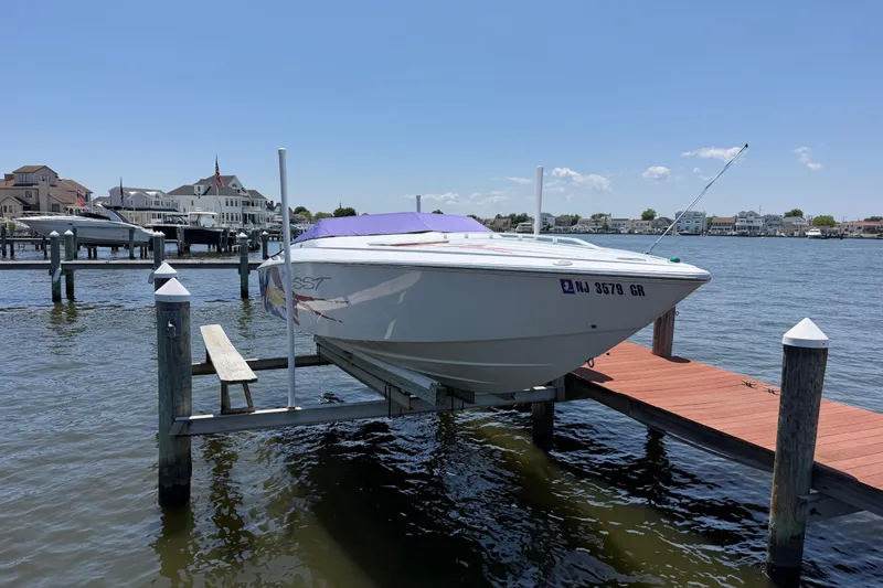 Slide: The Image of 2002 Baja 25 Outlaw boat docked on a sunny waterfront with houses in the background. - 7