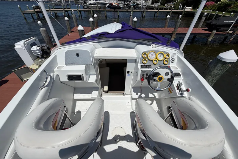 Slide: The Image of 2002 Baja 25 Outlaw boat interior with steering wheel, gauges, and seating at a dock. - 14