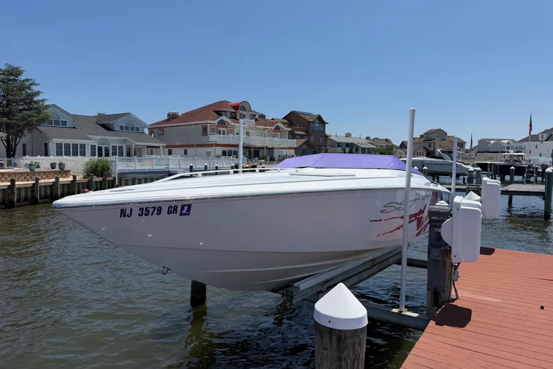 Slide: The Image of 2002 Baja 25 Outlaw speedboat docked at a marina, surrounded by waterfront homes. - 8