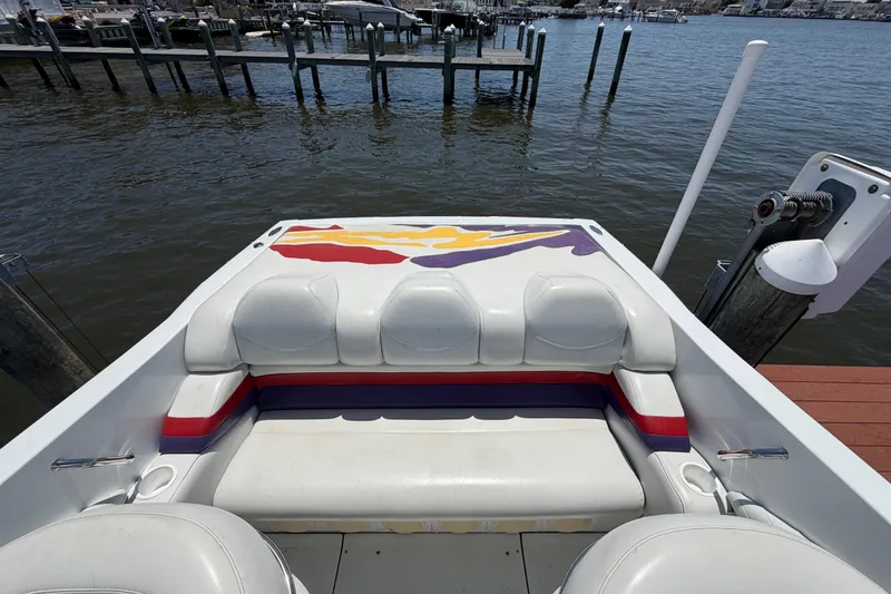 Slide: The Image of 2002 Baja 25 Outlaw boat interior with colorful seating at a dock. - 13