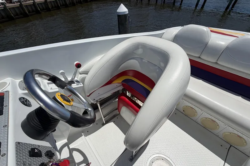 Slide: The Image of 2002 Baja 25 Outlaw boat cockpit with steering wheel and colorful seating. - 16