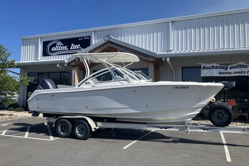 The Image of 2018 Edgewater 248CX Crossover boat on trailer outside Collins Inc. dealership. - 1