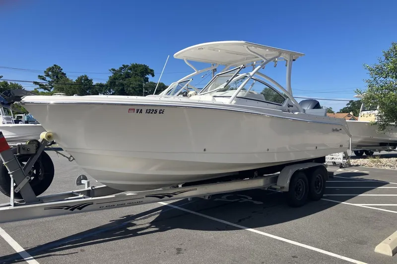 Slide: The Image of 2018 Edgewater 248CX Crossover boat on trailer in parking lot under clear blue sky. - 4
