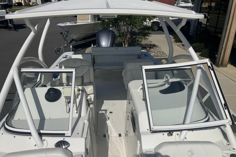 Slide: The Image of 2018 Edgewater 248CX Crossover boat with open cockpit and dual consoles, parked outdoors. - 11