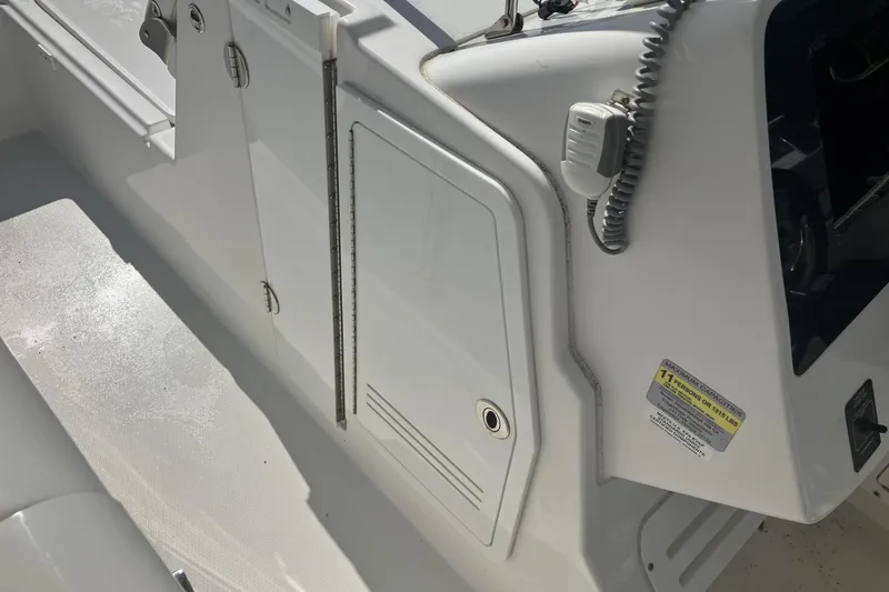 Slide: The Image of 2018 Edgewater 248CX Crossover boat interior, featuring white console and seating area. - 15