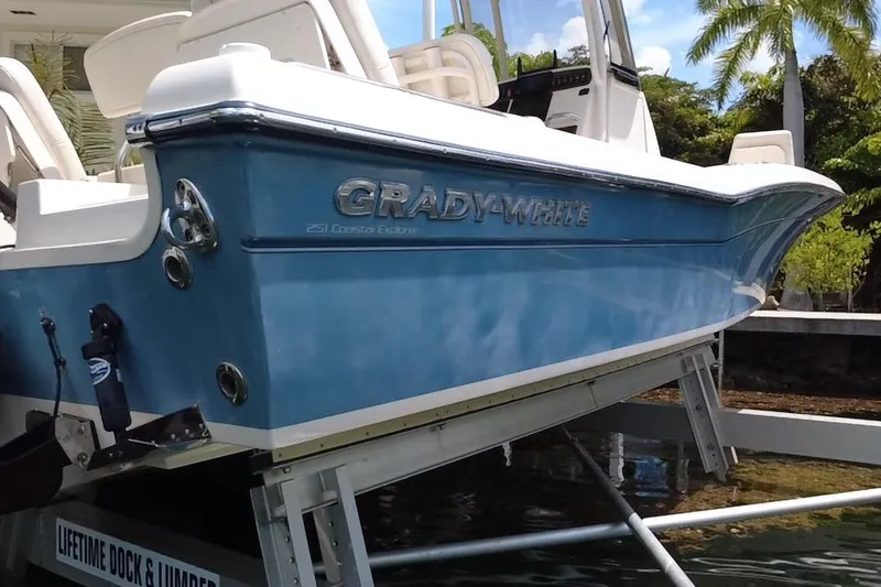 Slide: The Image of 2021 Grady-White 251 Coastal Explorer boat on lift, blue hull, tropical background. - 10