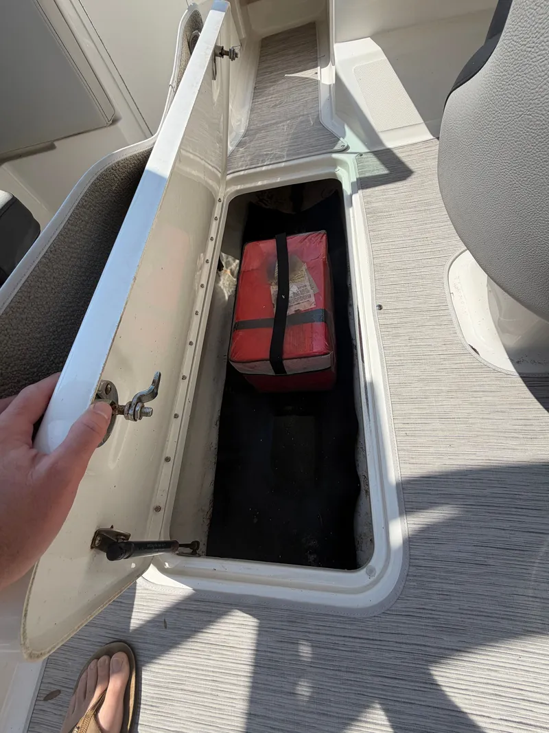 Slide: The Image of An open storage compartment on a boat with a red bag inside. - 16