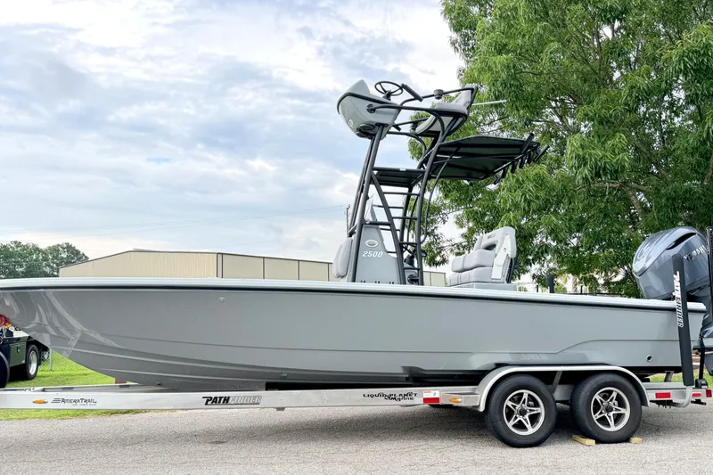The Image of 2026 Pathfinder 2500 Hybrid on a trailer, featuring T-tops and an outboard motor, parked by a tree. - 0