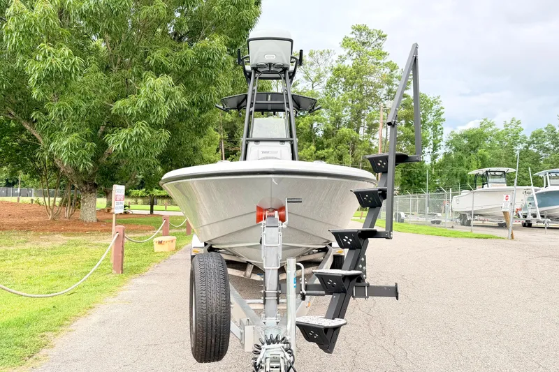 Slide: The Image of 2026 Pathfinder 2500 Hybrid boat on trailer, parked outdoors with lush greenery. - 2