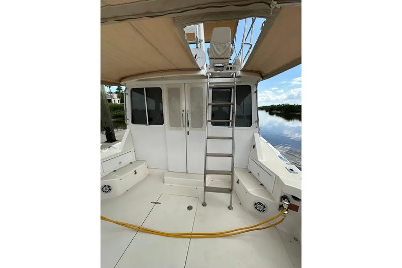 Slide: The Image of 2007 True North 38 Heritage boat with ladder and canopy, docked by calm water. - 23