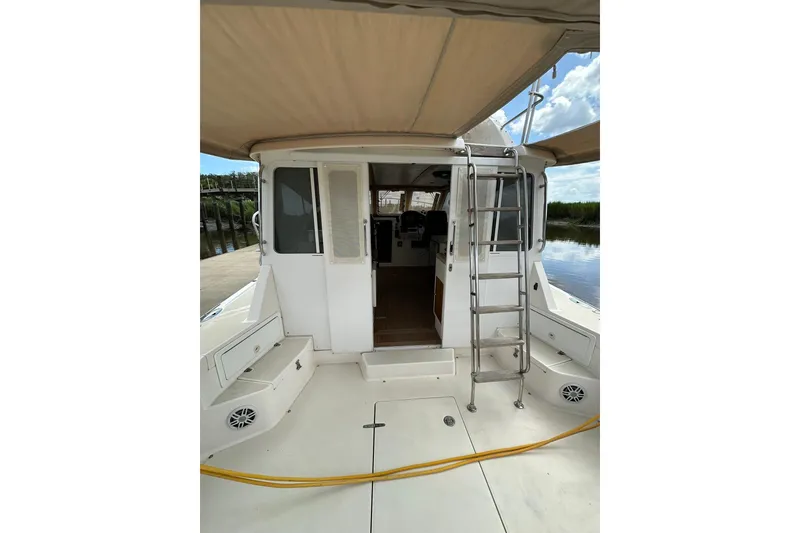 Slide: The Image of 2007 True North 38 Heritage boat deck with ladder and canopy, docked by calm water. - 50