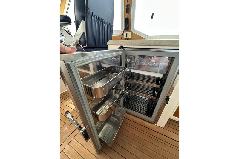 Slide: The Image of Open stainless steel refrigerator on 2007 True North 38 Heritage boat, showcasing interior storage. - 62